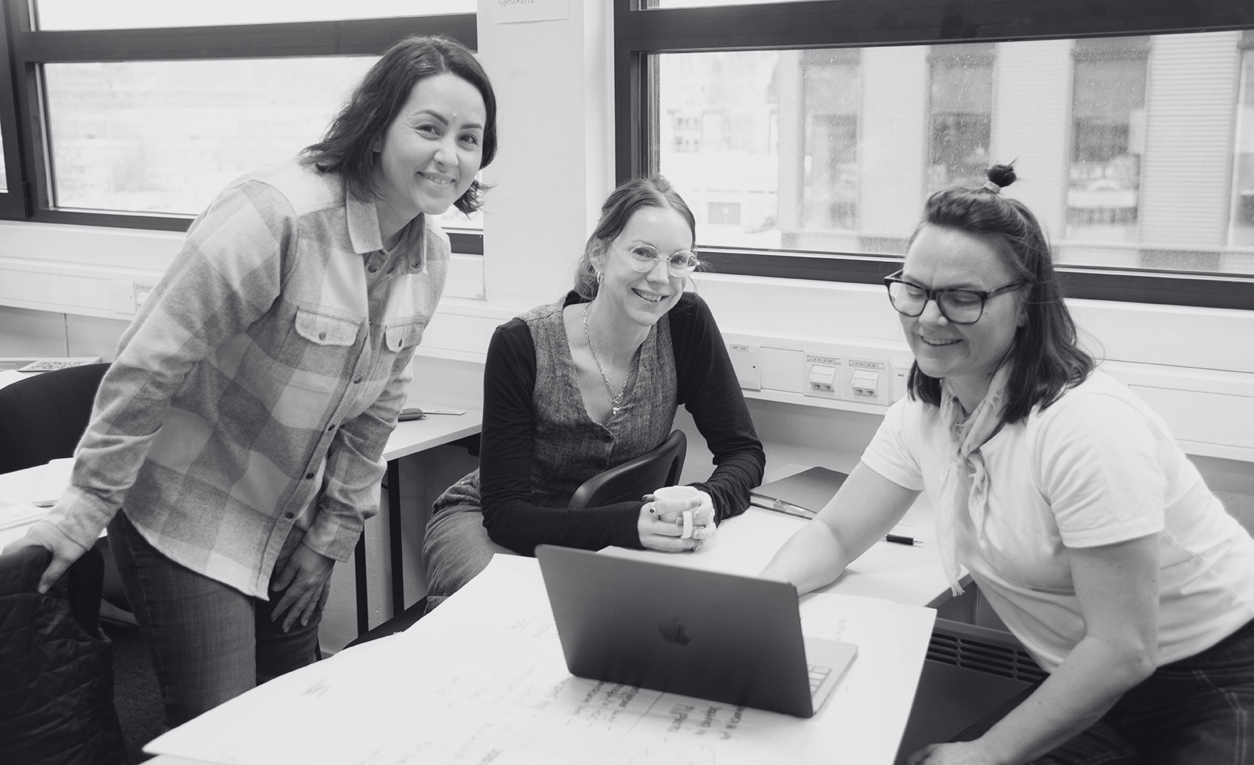 Three woman sitting around a computer, smiling